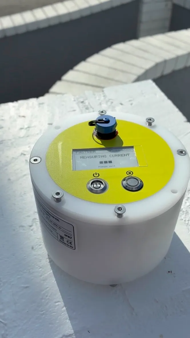 The buoy's display reading MEASURING CURRENT with a progress indicator and the words Please wait underneath.
