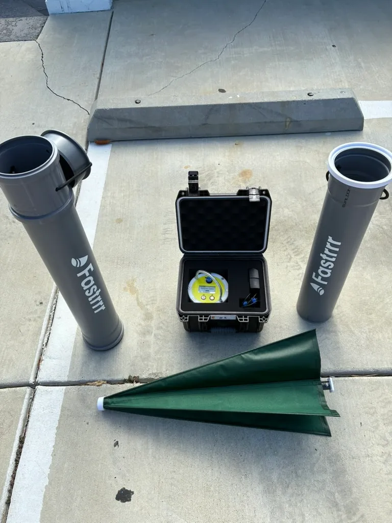 The full kit laid out: two grey Fastrrr tubes, the black case holding the buoy, and the green drogue folded closed.